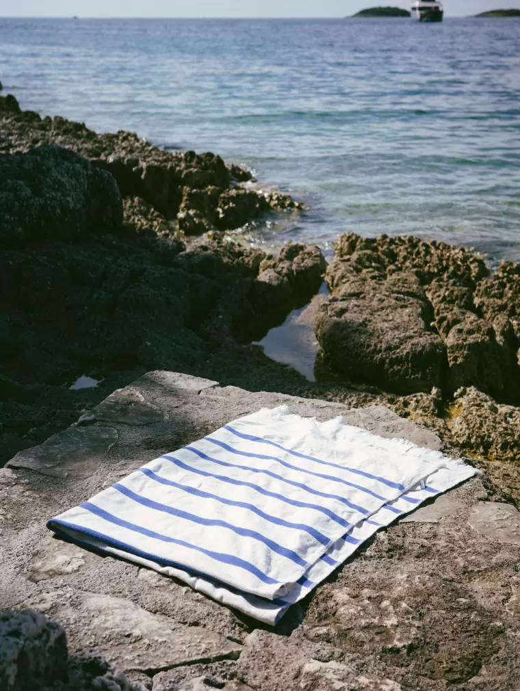 Beach towel on volcanic rocks by the sea