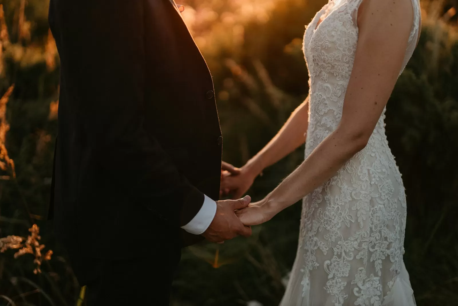 Bride and groom holding hands at sunset